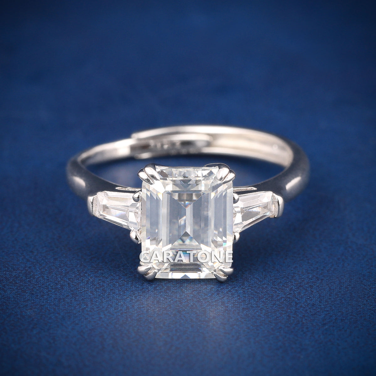 Premium Luxury Emerald Cut Solitaire Ring With Brilliant White Center Stone, Elegant Trapezoid Side Stones, Classic Silver Tone Band And Exclusive Designer Engagement Jewelry For Women