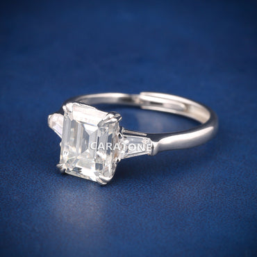 Premium Luxury Emerald Cut Solitaire Ring With Brilliant White Center Stone, Elegant Trapezoid Side Stones, Classic Silver Tone Band And Exclusive Designer Engagement Jewelry For Women