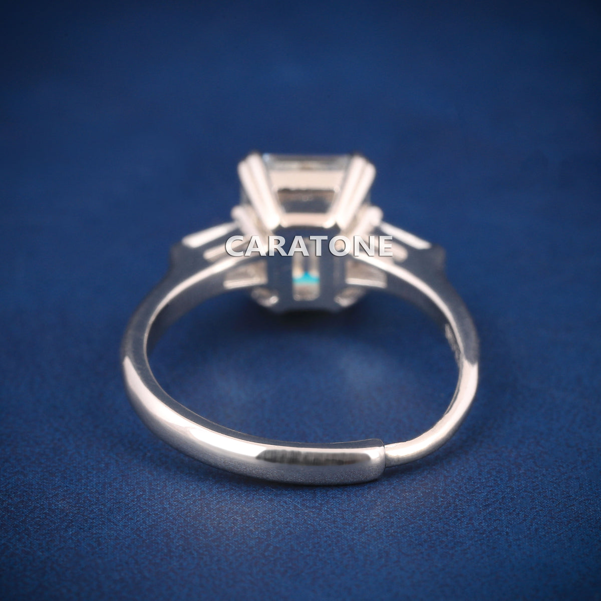 Premium Luxury Emerald Cut Solitaire Ring With Brilliant White Center Stone, Elegant Trapezoid Side Stones, Classic Silver Tone Band And Exclusive Designer Engagement Jewelry For Women