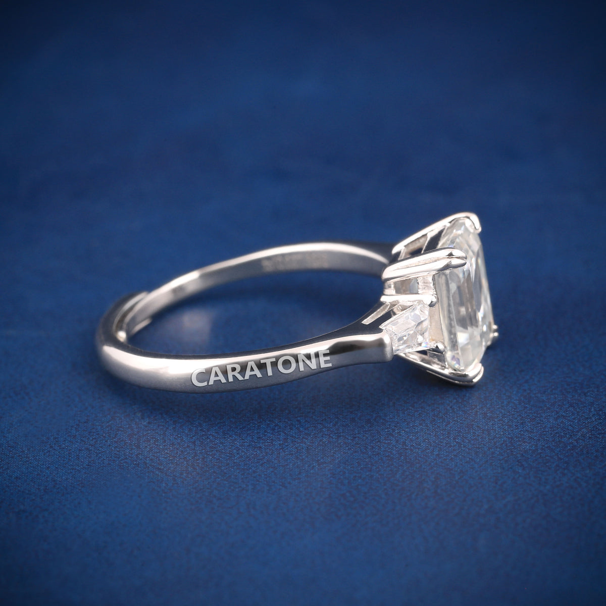 Premium Luxury Emerald Cut Solitaire Ring With Brilliant White Center Stone, Elegant Trapezoid Side Stones, Classic Silver Tone Band And Exclusive Designer Engagement Jewelry For Women